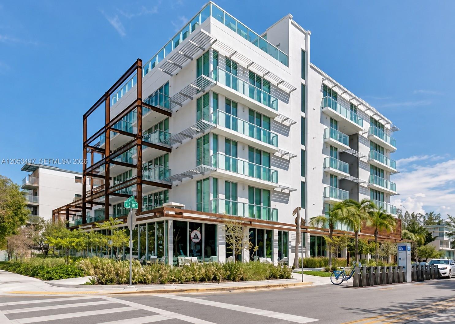 A modern multi-story white apartment building with glass balconies and a metal frame exterior — MIAMI BEACH, FL