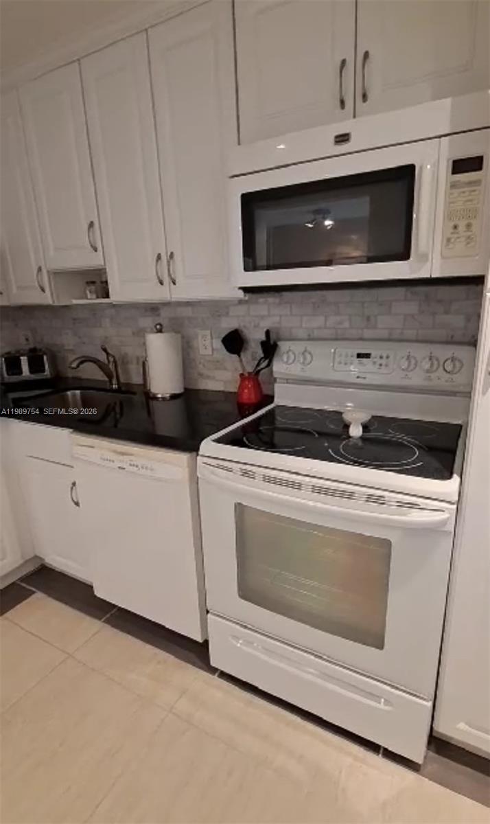 A white kitchen features a black countertop, white cabinets, and white appliances — 3774 Inverrary Blvd # 103P, Lauderhill FL 33319, LAUDERHILL, FL