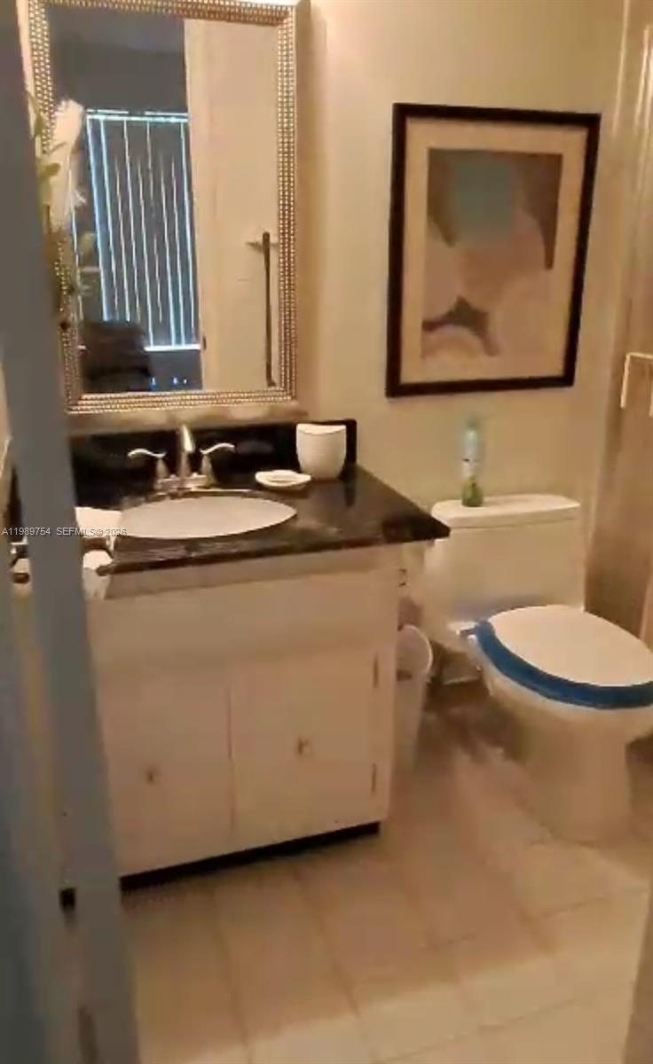 A bathroom features a vanity with a dark countertop, a framed mirror, and a toilet — 3774 Inverrary Blvd # 103P, Lauderhill FL 33319, LAUDERHILL, FL