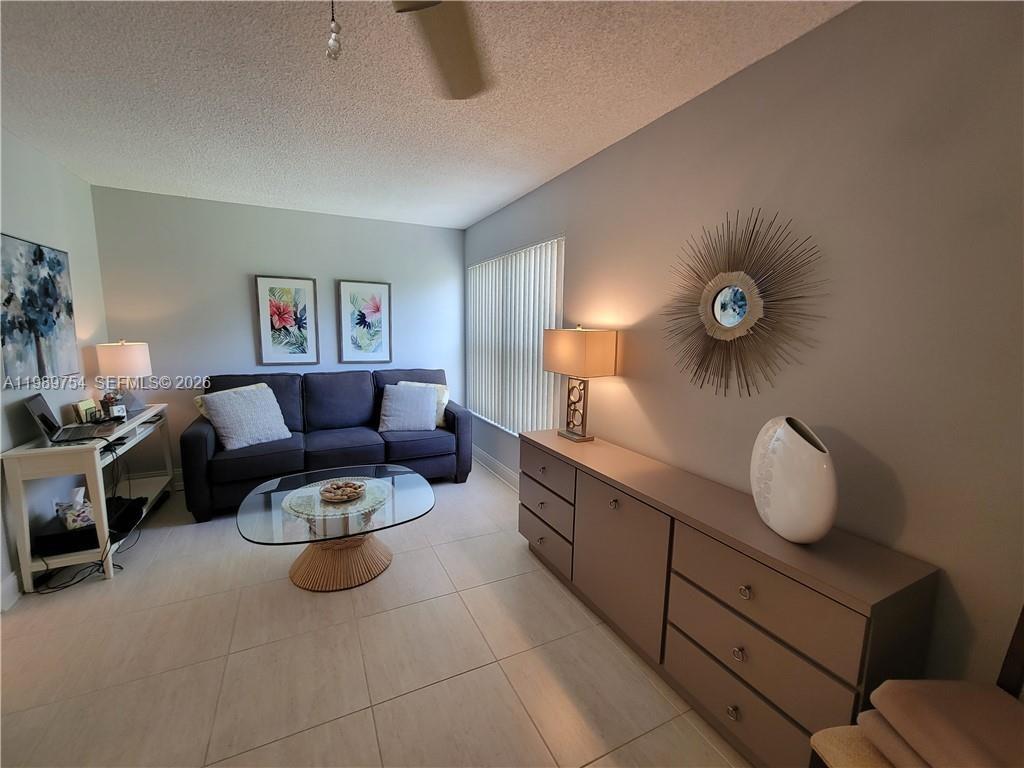 A living room features a dark sofa, a glass coffee table, and a long dresser — 3774 Inverrary Blvd # 103P, Lauderhill FL 33319, LAUDERHILL, FL