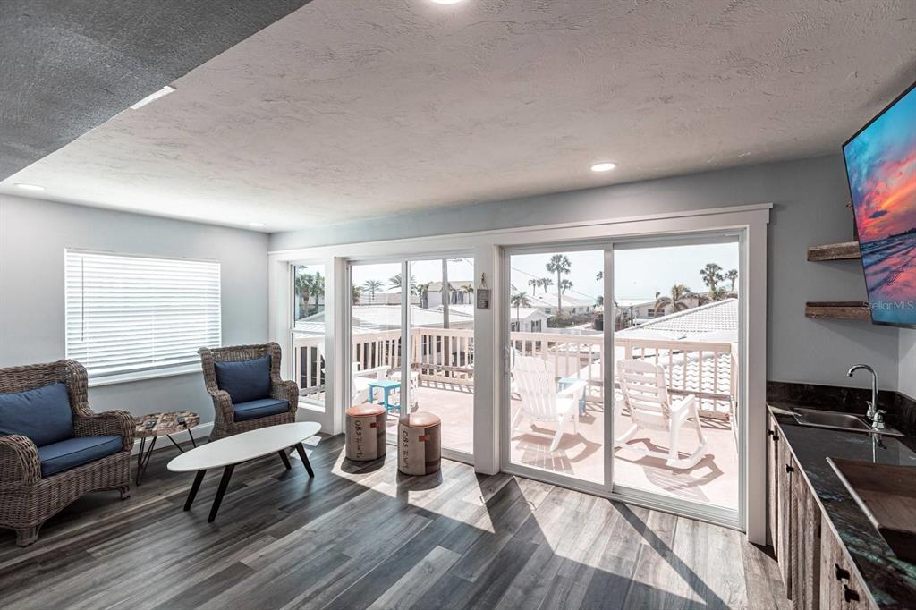 A living area with wicker chairs, a kitchenette, and sliding doors opening to a deck — 6020 MIDNIGHT PASS ROAD UNIT 52A, SARASOTA, FL