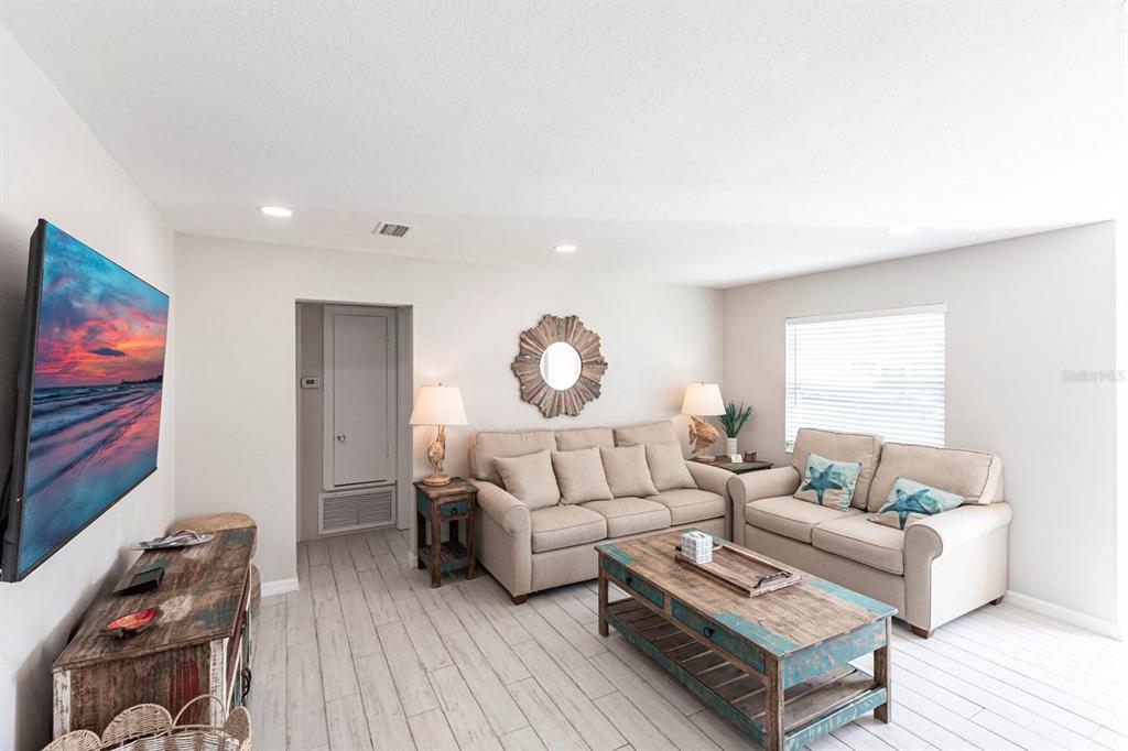 A living room features light tile flooring, two beige sofas, a rustic coffee table, and a television — 6020 MIDNIGHT PASS ROAD UNIT 52A, SARASOTA, FL