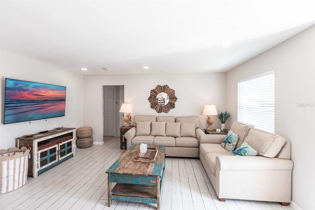 A living room features light wood-look flooring, a beige sectional sofa, and a rustic coffee table — 6020 MIDNIGHT PASS ROAD UNIT 52A, SARASOTA, FL