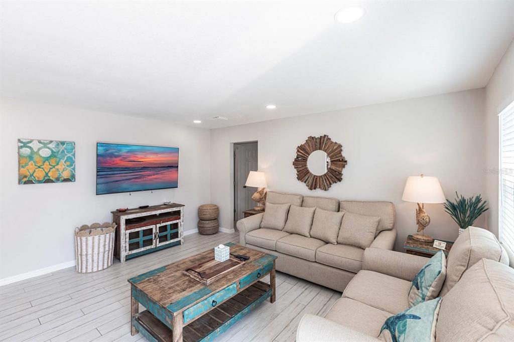 A living room features light wood-look flooring, a beige sofa, and a rustic coffee table — 6020 MIDNIGHT PASS ROAD UNIT 52A, SARASOTA, FL