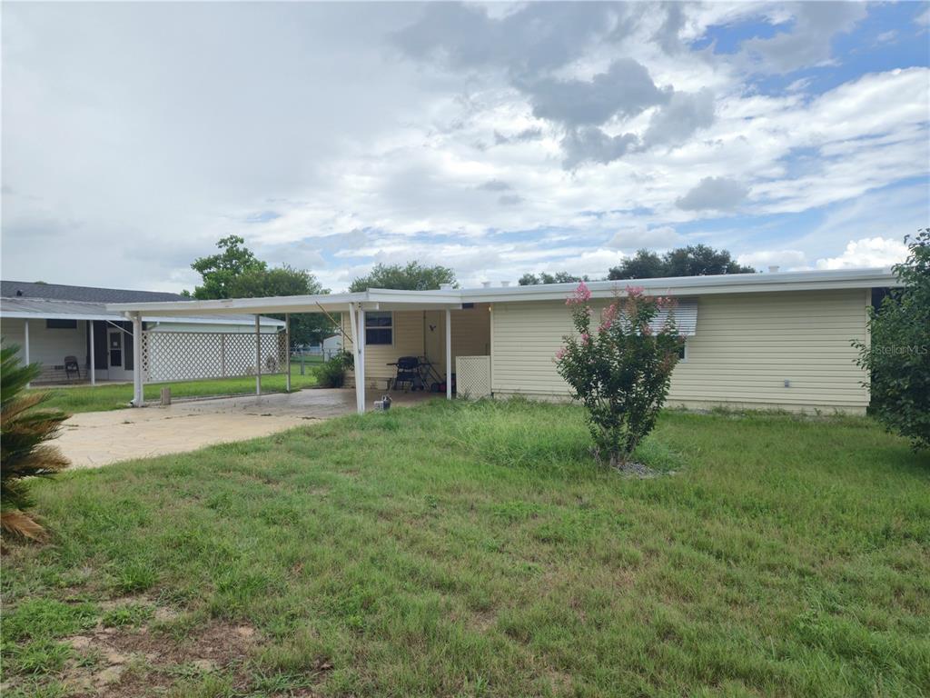 A single-story house with light yellow siding and a covered carport over a concrete driveway — 6605 NE 1ST LANE, OCALA, FL