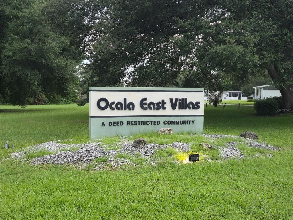 A sign for Ocala East Villas stands in a grassy area beneath large trees — 6605 NE 1ST LANE, OCALA, FL