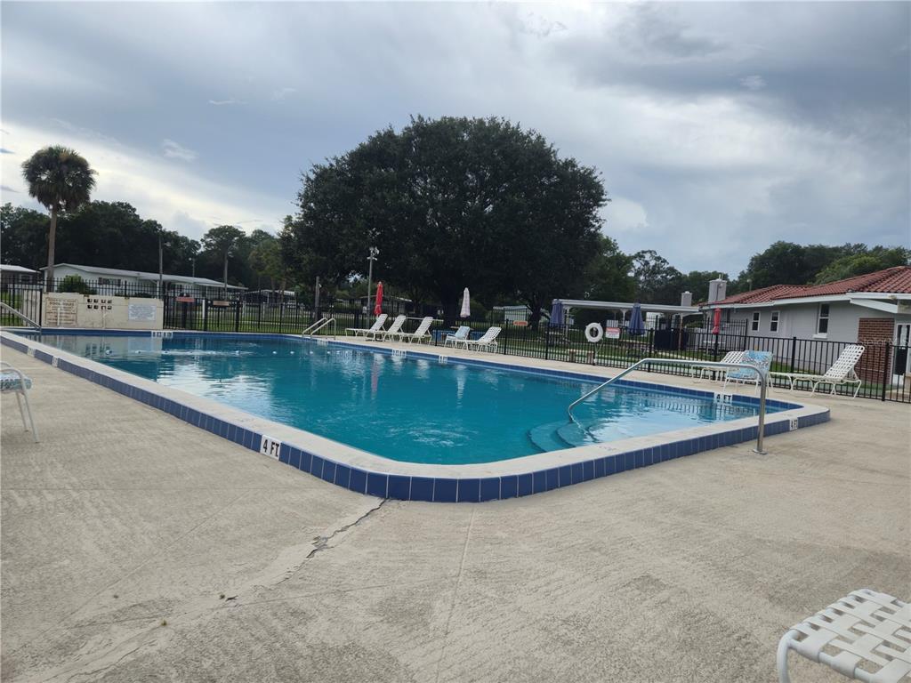 An outdoor rectangular swimming pool with a concrete deck and surrounding metal fencing — 6605 NE 1ST LANE, OCALA, FL