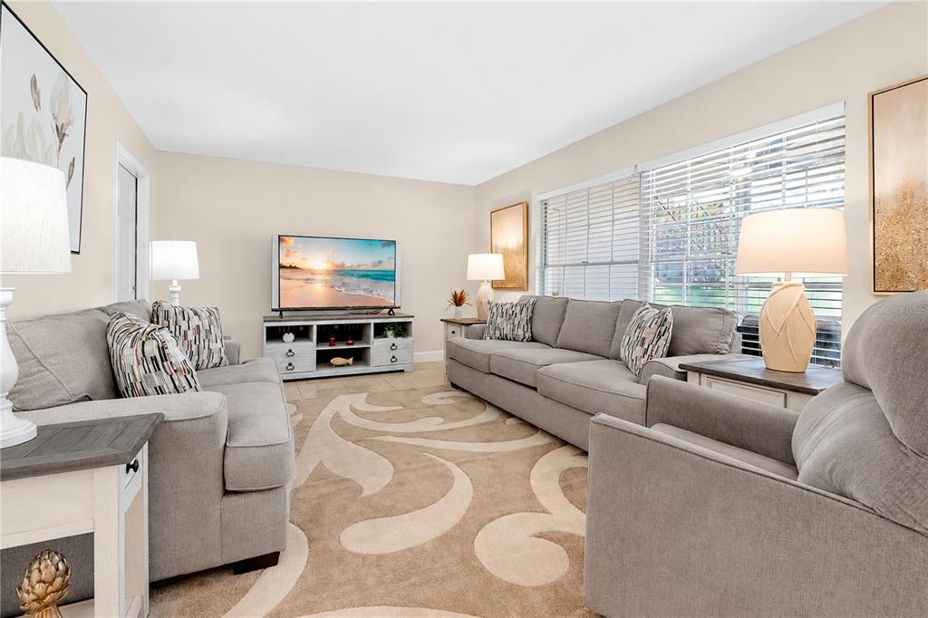 A living room features gray sofas, a patterned area rug, and a television on a stand — 1018 PLANTATION DRIVE UNIT A18, KISSIMMEE, FL