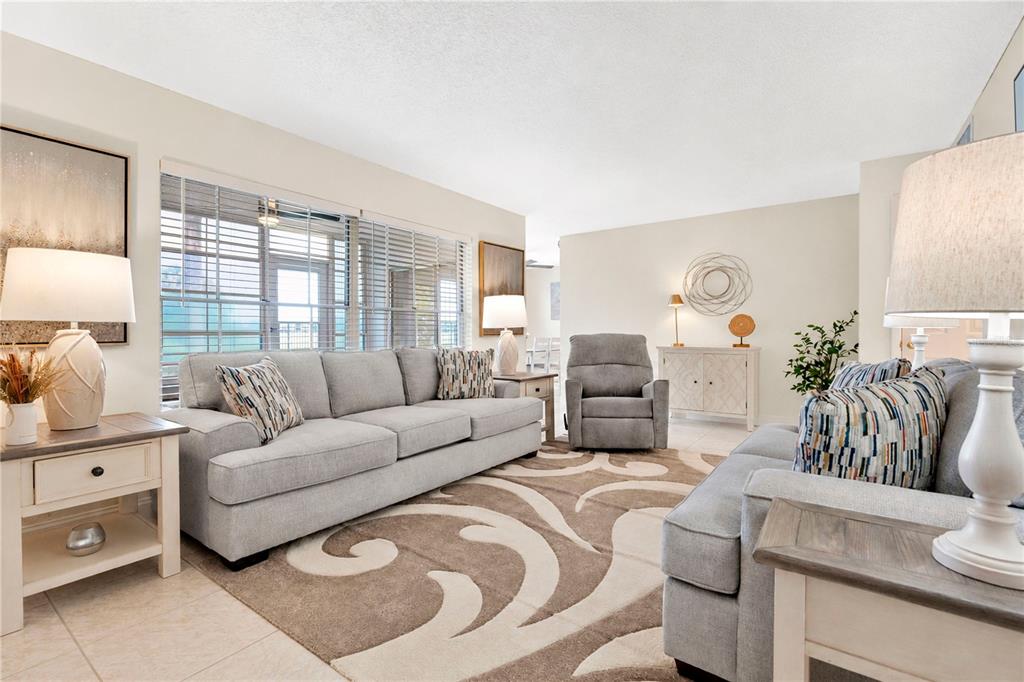 A living room features light gray sofas, a patterned area rug, and neutral-toned furniture — 1018 PLANTATION DRIVE UNIT A18, KISSIMMEE, FL