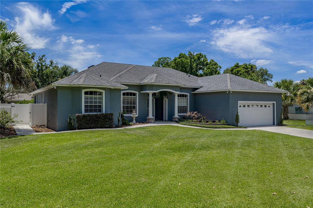A single-story gray house with a two-car garage and a large front lawn — 1113 SUGARTREE DRIVE N, LAKELAND, FL