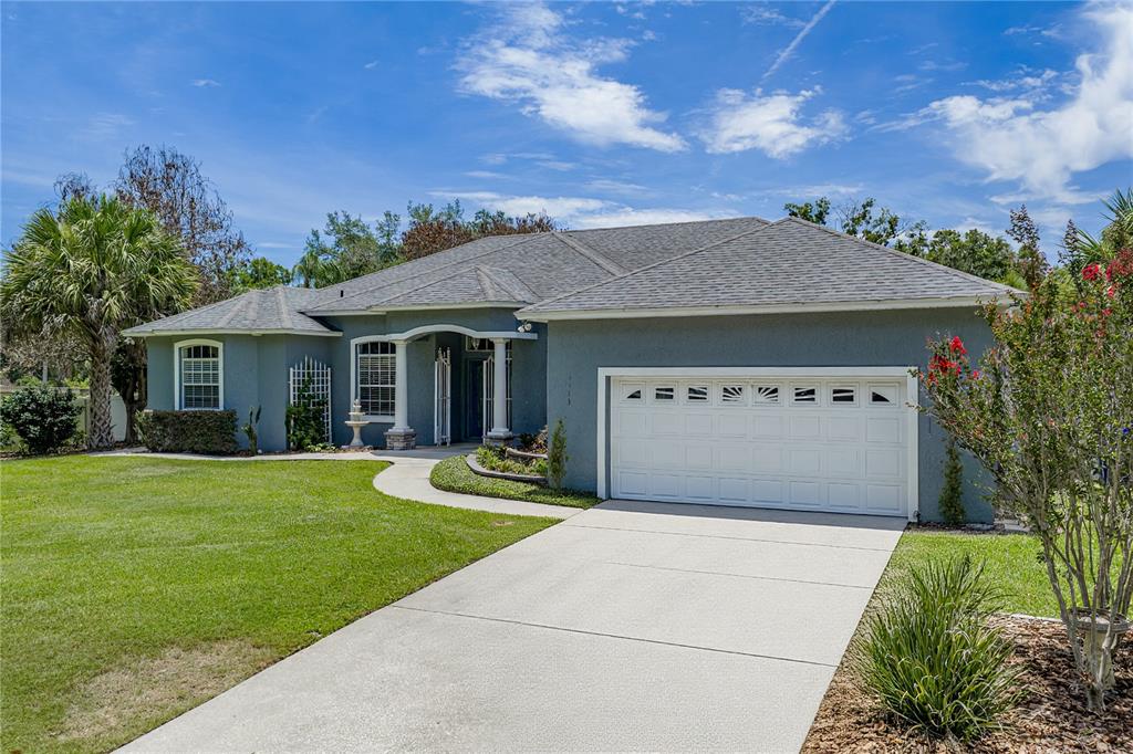 A single-story gray house with a white garage door and a concrete driveway — 1113 SUGARTREE DRIVE N, LAKELAND, FL