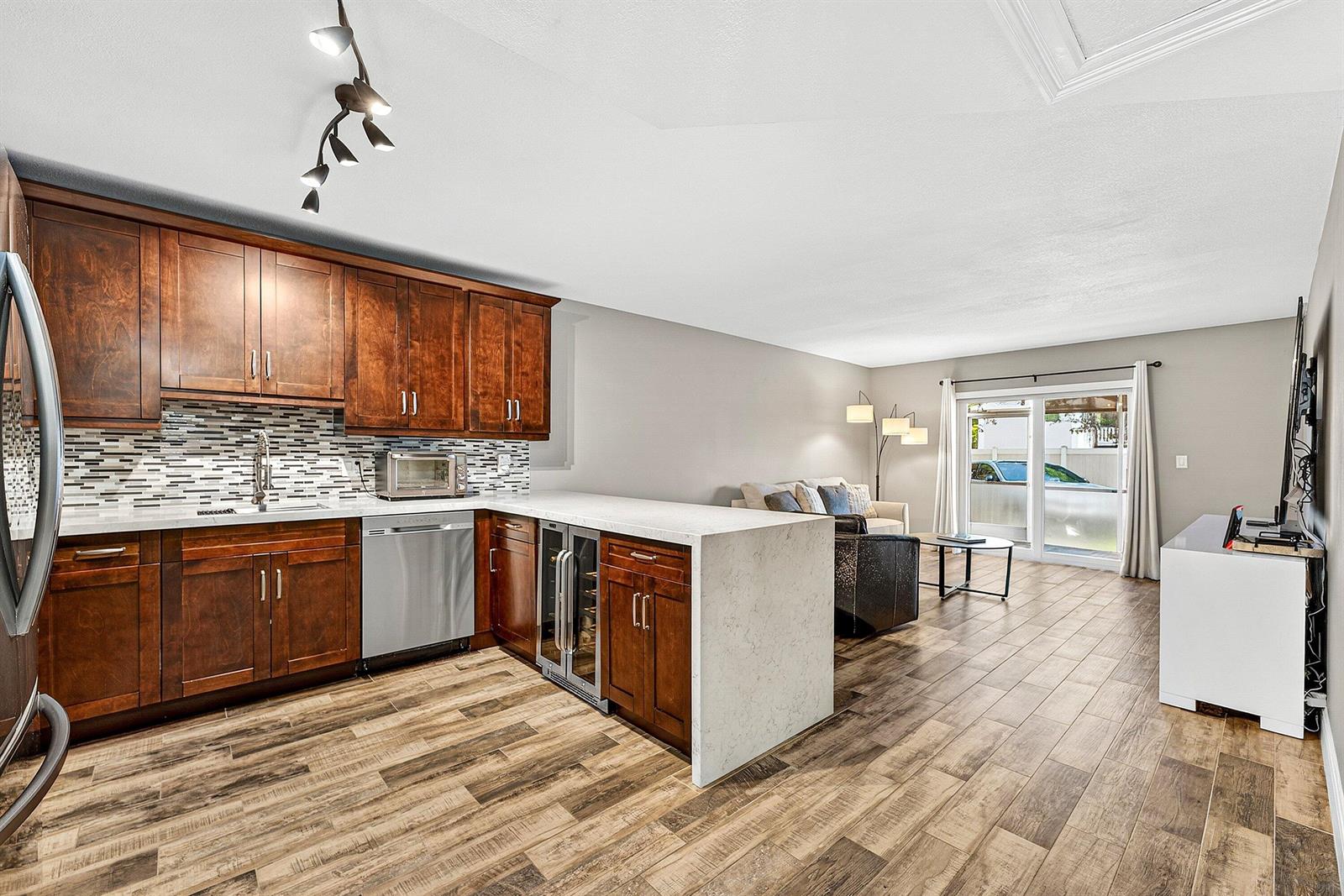 A kitchen with dark wood cabinets and a white stone peninsula opens to a living area — 101 E Mcnab Road # 304, Pompano Beach FL 33060, POMPANO BEACH, FL