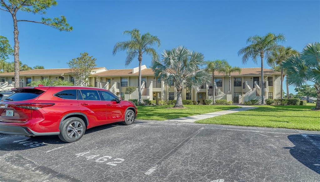 A red SUV is parked in a lot in front of a two-story apartment building — 4462 WEYBRIDGE STREET UNIT 72, SARASOTA, FL
