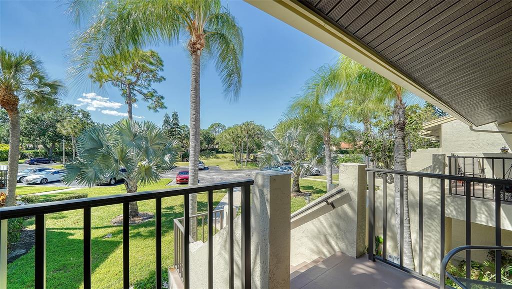 A view from a second-story balcony overlooking a parking lot, green lawn, and palm trees — 4462 WEYBRIDGE STREET UNIT 72, SARASOTA, FL
