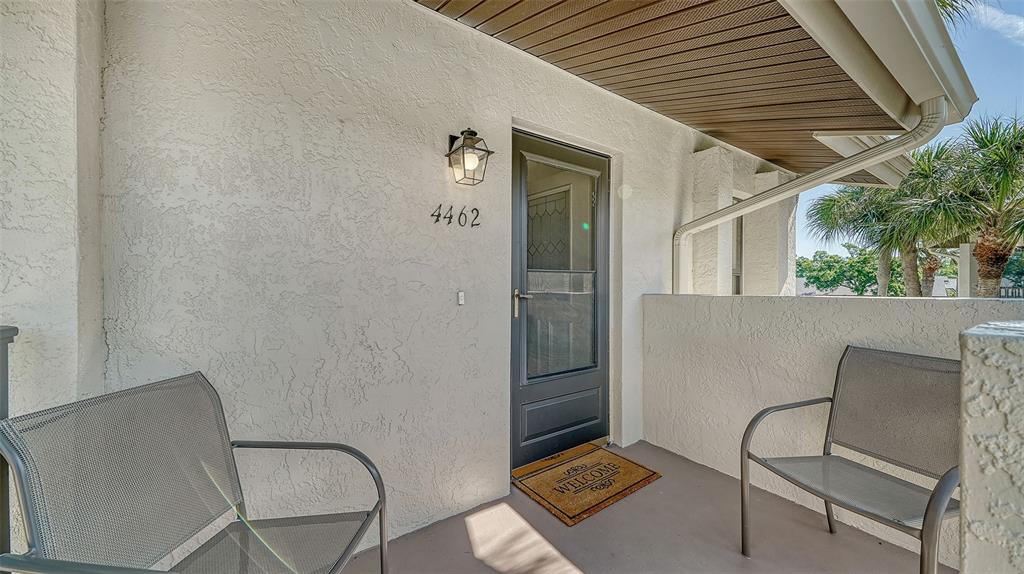 An exterior entryway features a dark door, two metal chairs, and a welcome mat — 4462 WEYBRIDGE STREET UNIT 72, SARASOTA, FL