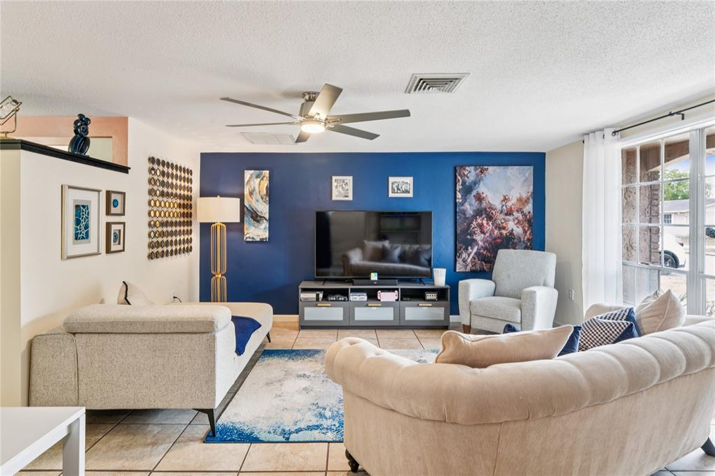 A living room features a blue accent wall, a television, and light-colored furniture — 6805 ALTAVISTA STREET, PORT RICHEY, FL