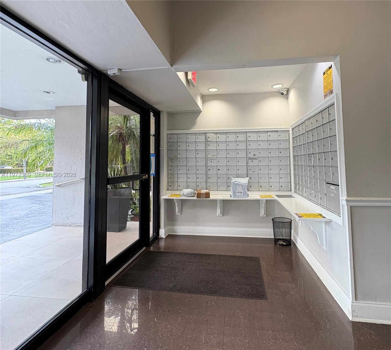 This indoor mailroom features rows of metal mailboxes, a white counter, and a glass door — 3500 NE 135 # 502, North Miami FL 33181, NORTH MIAMI, FL