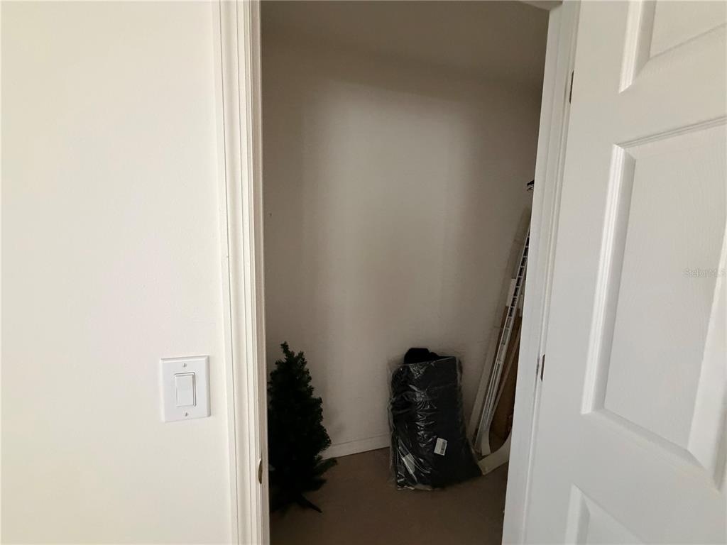 A small, empty closet with a white door, a light switch, and some stored items — 456 WATERFORD WAY, KISSIMMEE, FL