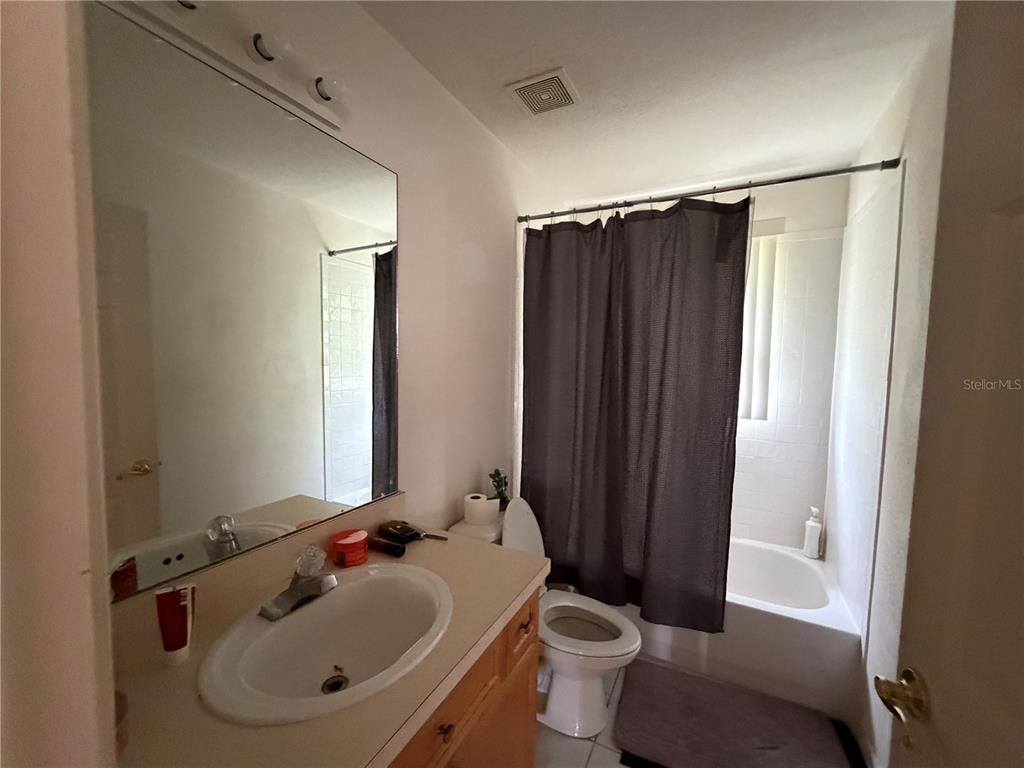 A bathroom features a vanity with a mirror, a toilet, and a shower-tub combination — 456 WATERFORD WAY, KISSIMMEE, FL