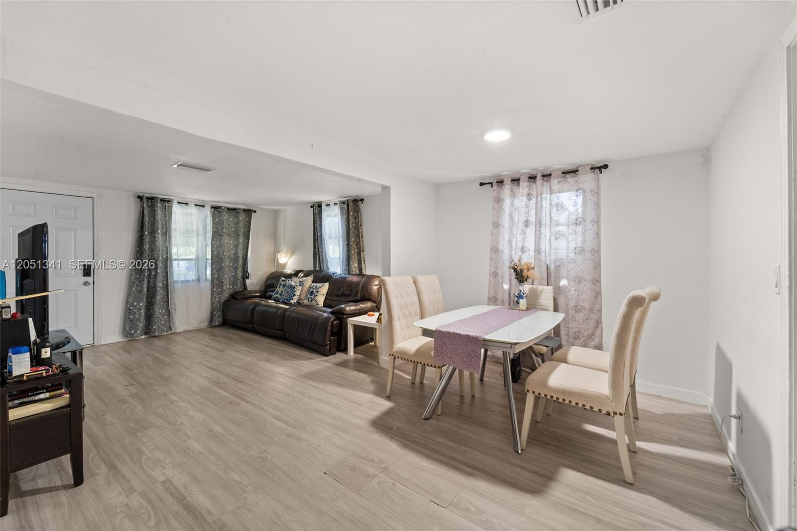 This open-concept living and dining area features light wood-look flooring and white walls — 349 NW 41st St, Miami FL 33127, MIAMI, FL