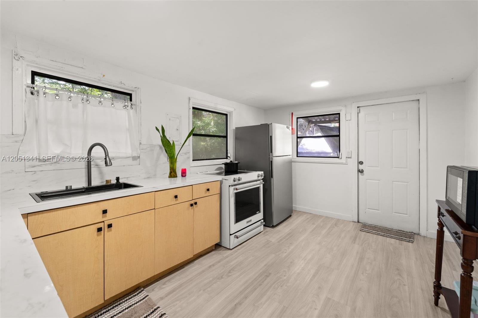 A kitchen features light wood cabinets, white countertops, stainless steel appliances, and light wood flooring — 349 NW 41st St, Miami FL 33127, MIAMI, FL