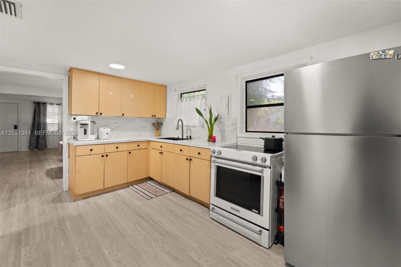 A kitchen features light wood cabinets, white countertops, stainless steel appliances, and light wood flooring — 349 NW 41st St, Miami FL 33127, MIAMI, FL