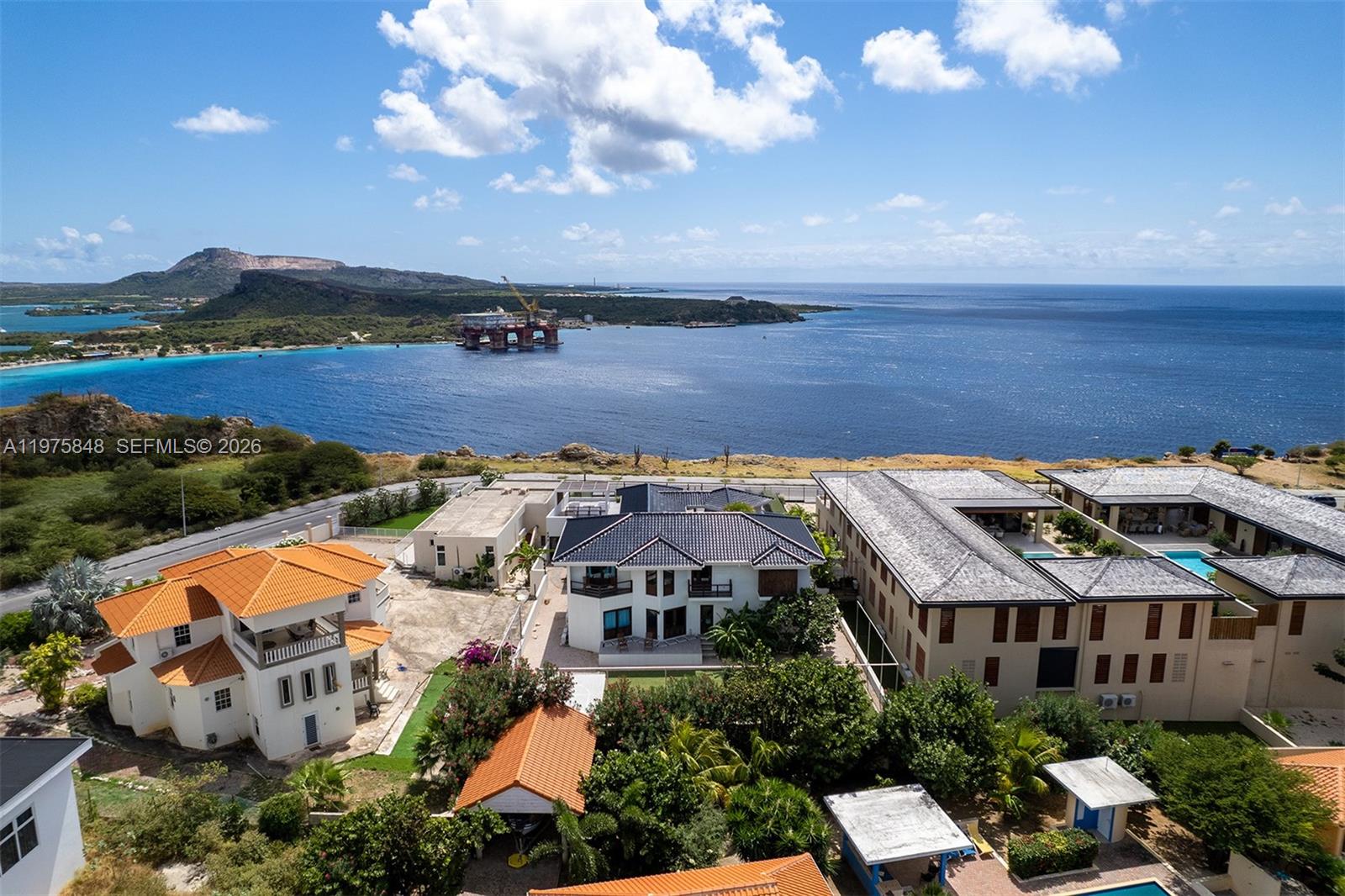 An aerial view shows several villas with tiled roofs overlooking a bay with an oil rig — T17 Vista Royal, FL 0000, FL
