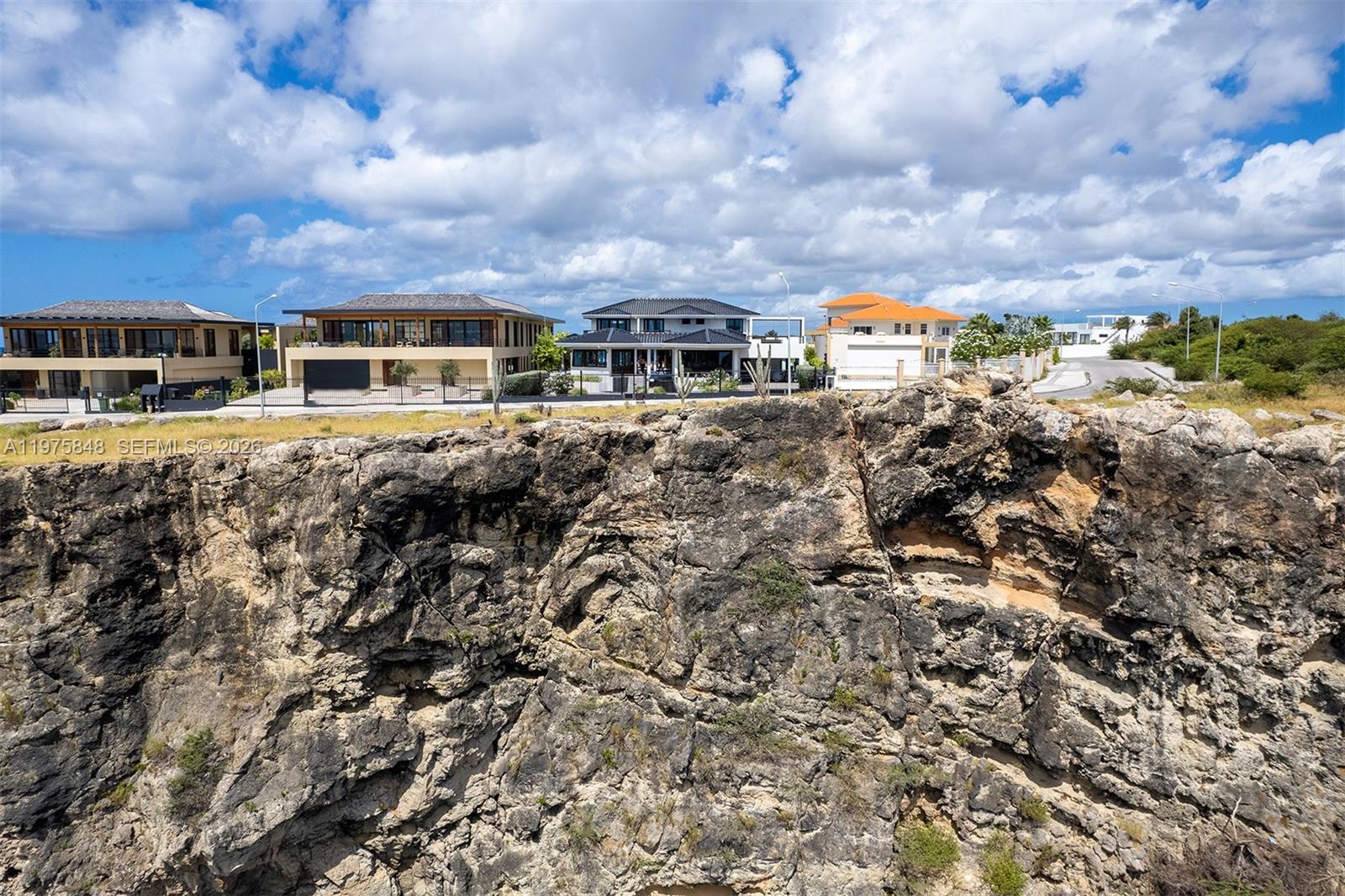 A rocky cliff face sits in the foreground below a row of modern residential houses — T17 Vista Royal, FL 0000, FL