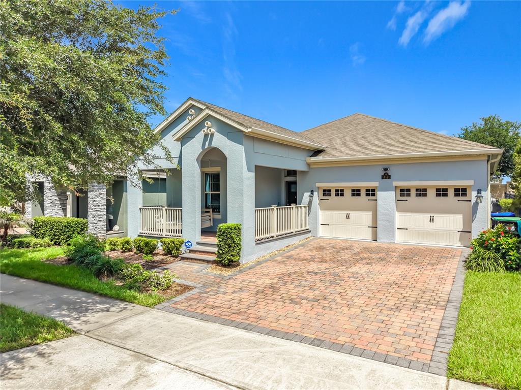 A light blue single-story house features a brick paver driveway and a covered front porch — 16131 HAMPTON CROSSING DRIVE, WINTER GARDEN, FL