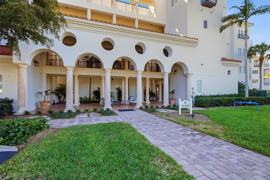 A paved walkway leads to the arched, columned entrance of a white multi-story building — 11200 HACIENDA DEL MAR BOULEVARD UNIT B-204, PLACIDA, FL