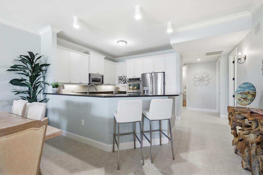 A kitchen features white cabinets, a dark countertop, a breakfast bar, and stainless steel appliances — 11200 HACIENDA DEL MAR BOULEVARD UNIT B-204, PLACIDA, FL