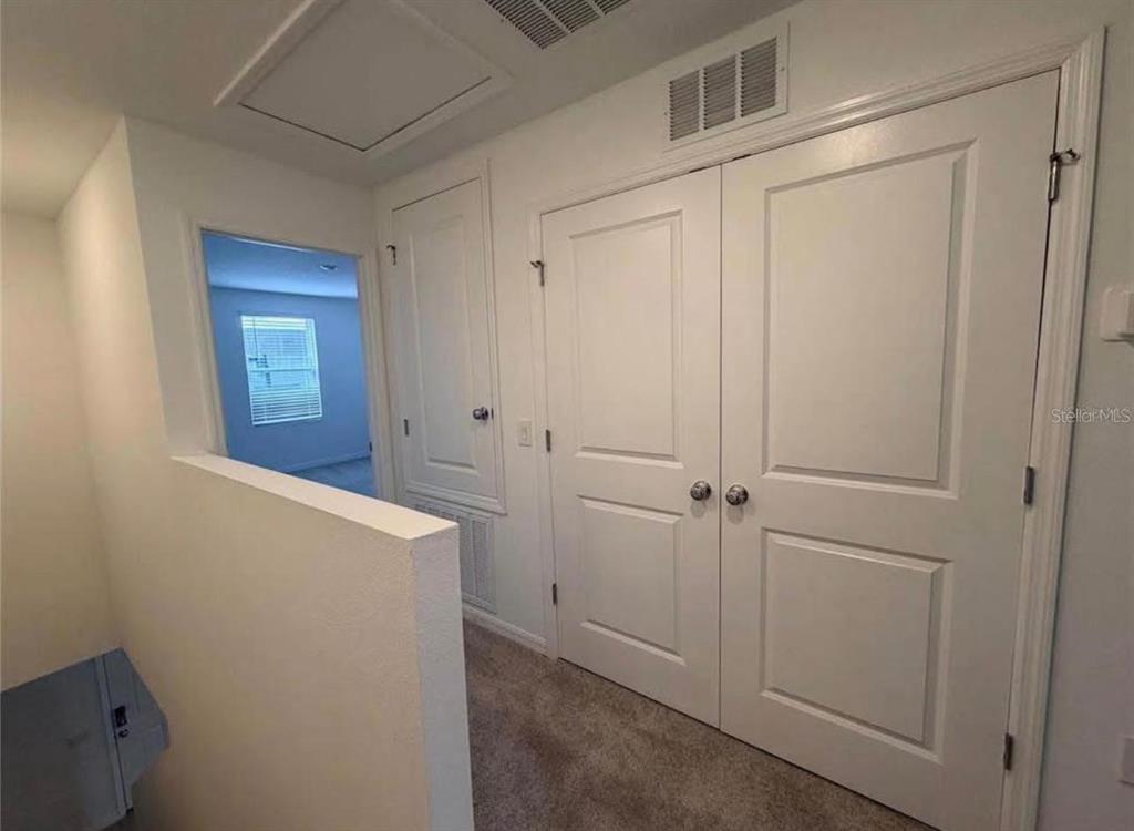 A carpeted hallway features a double-door closet, a single-door closet, and a view into a bedroom — 3356 COMPOSITION STREET, KISSIMMEE, FL
