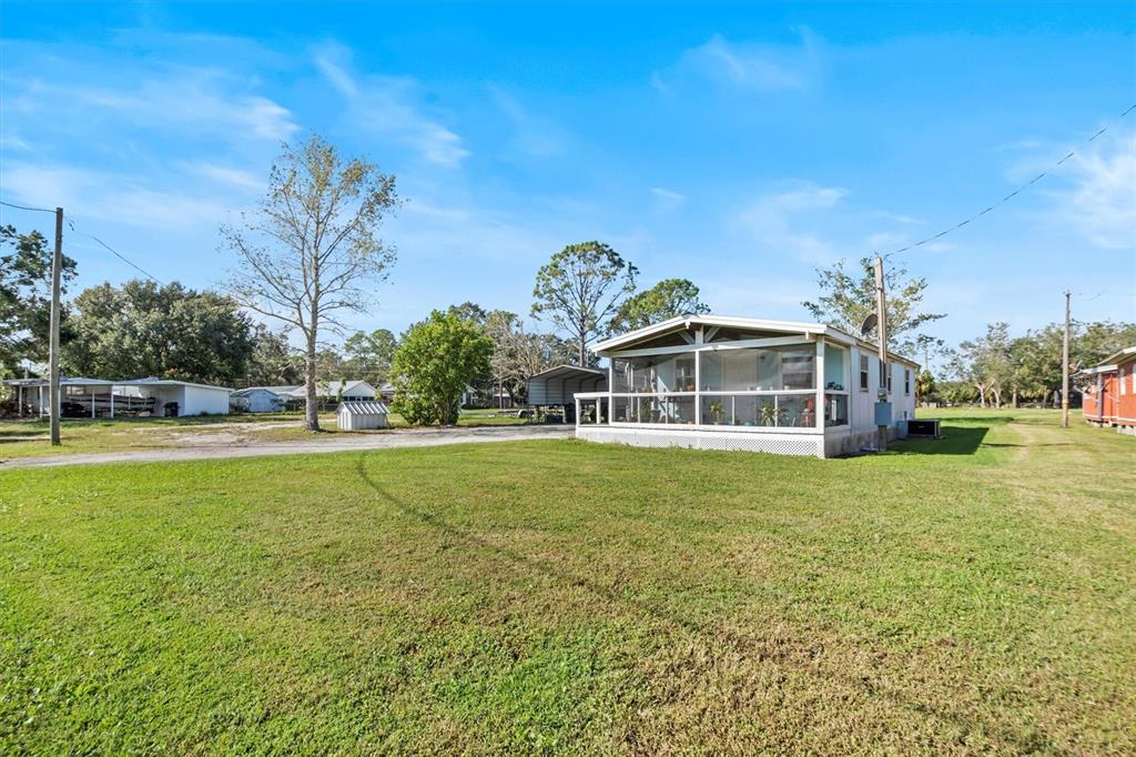 A single-story mobile home with a screened-in porch sits on a large, grassy lot — 3364 N MARINA PARKWAY, LAKE WALES, FL