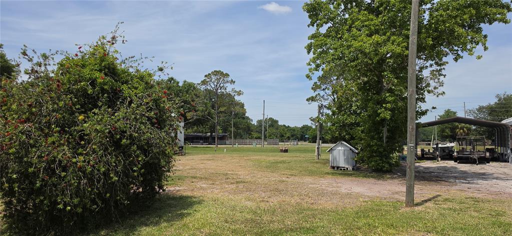 A large, grassy lot features a flowering bush, a small shed, and a metal carport — 3364 N MARINA PARKWAY, LAKE WALES, FL