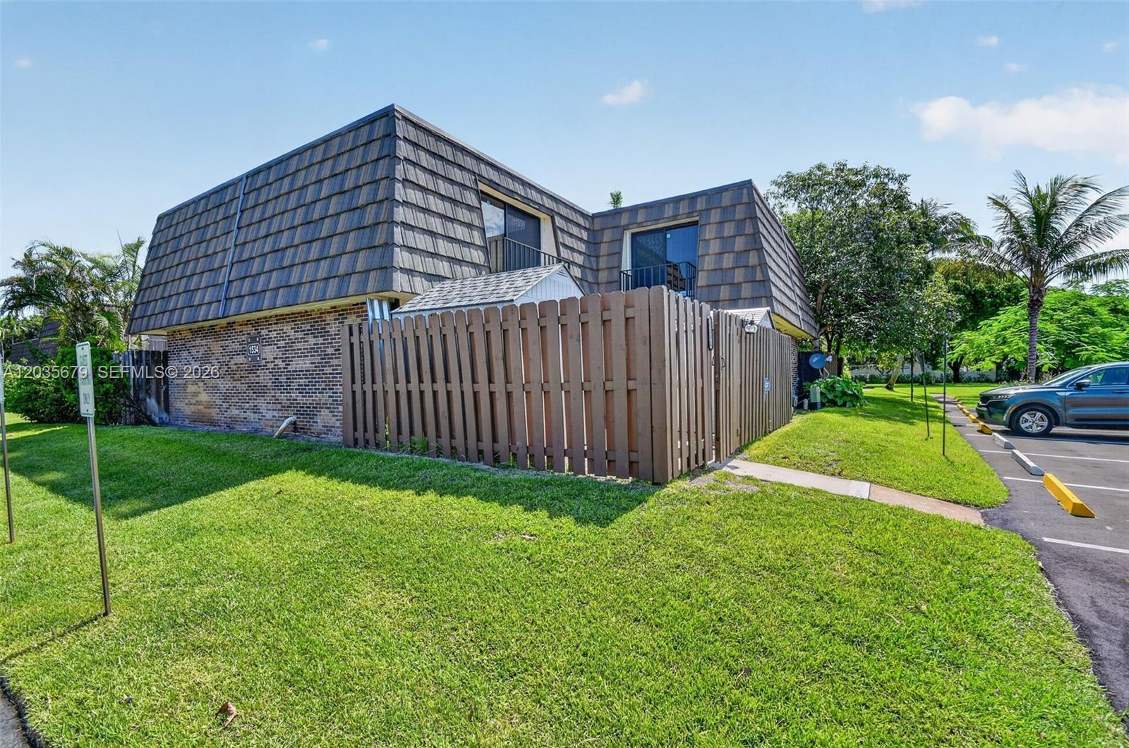 A two-story brick and mansard-roofed townhouse features a private fenced patio and adjacent parking — 1534 Forest Lakes Cir # A, West Palm Beach FL 33406, WEST PALM BEACH, FL