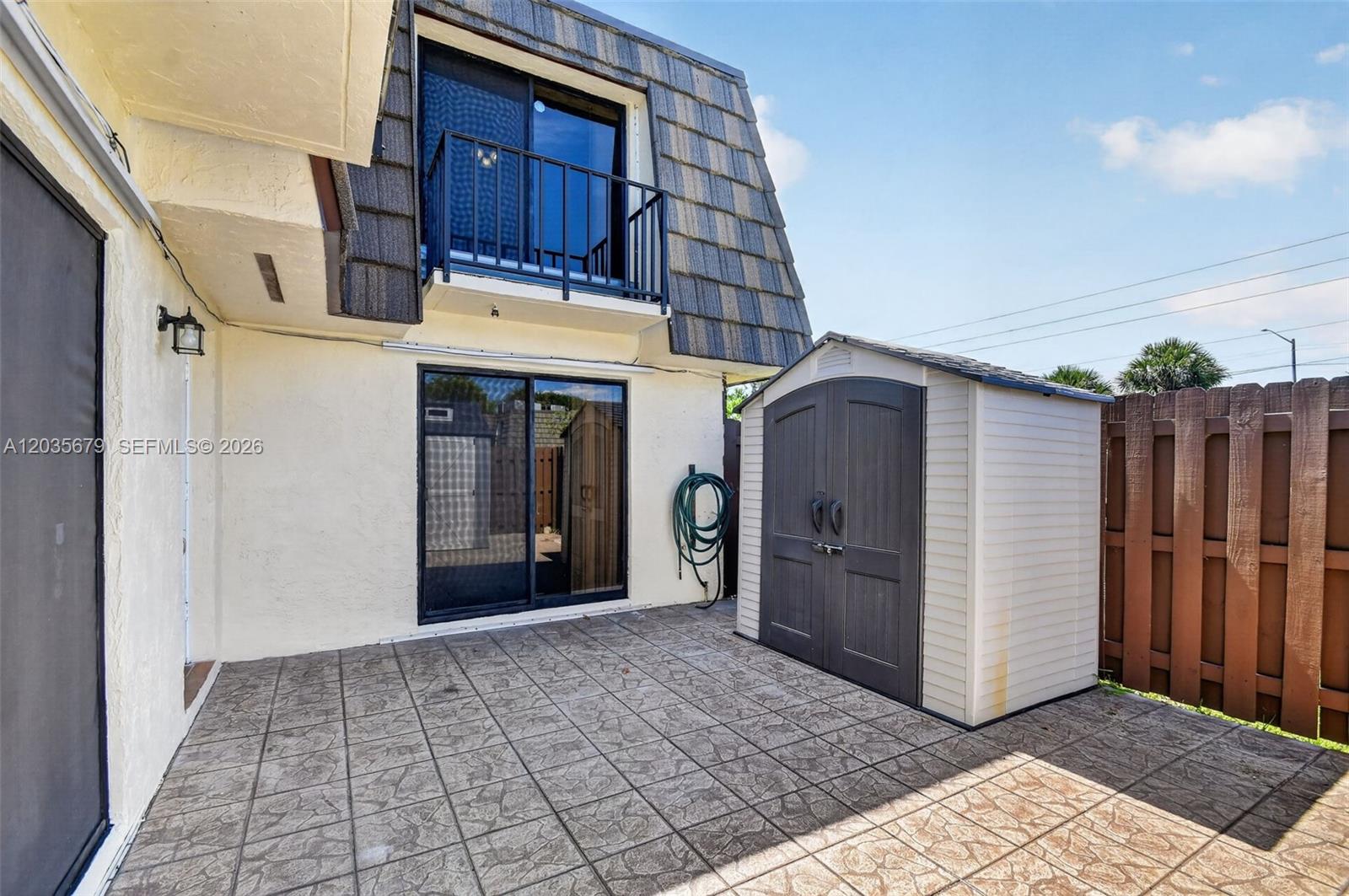 A patio features a storage shed, sliding glass doors, and a second-story balcony — 1534 Forest Lakes Cir # A, West Palm Beach FL 33406, WEST PALM BEACH, FL