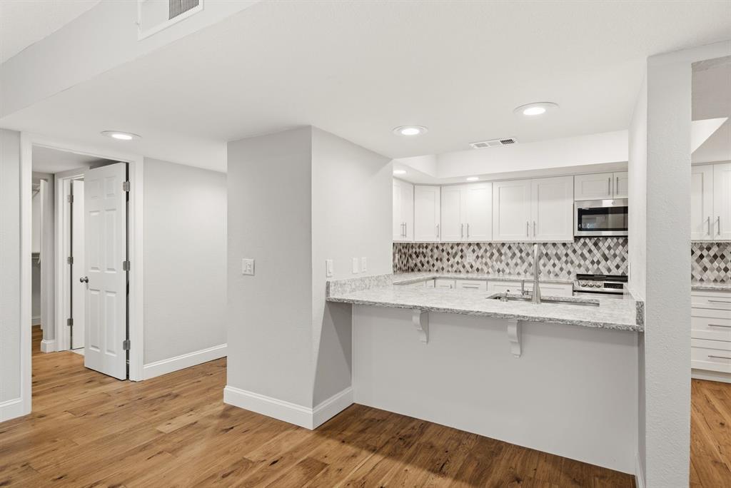 A kitchen with white cabinets, granite countertops, and a breakfast bar overlooks a living area — 125 MARINER DRIVE UNIT 125, TARPON SPRINGS, FL
