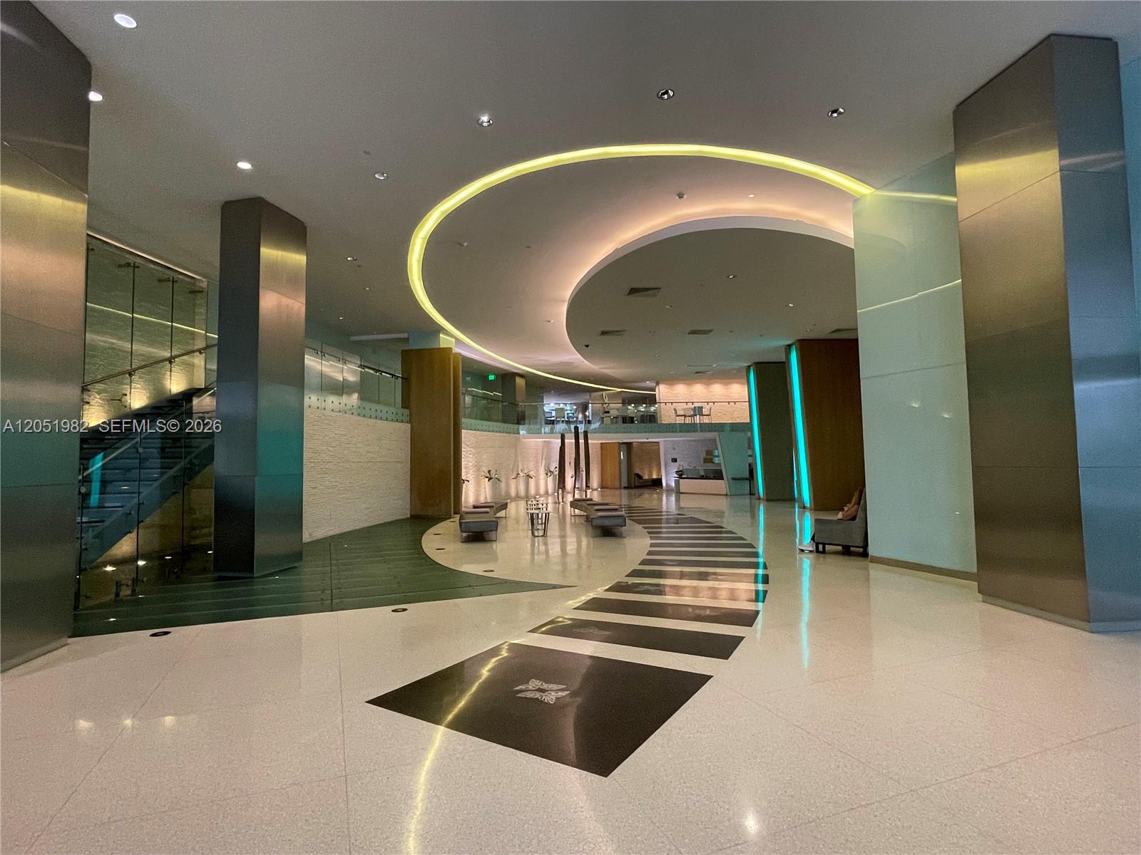 A modern building lobby features a curved ceiling light, polished floors, and metallic columns — 92 SW 3rd St # 5012, Miami FL 33130, MIAMI, FL