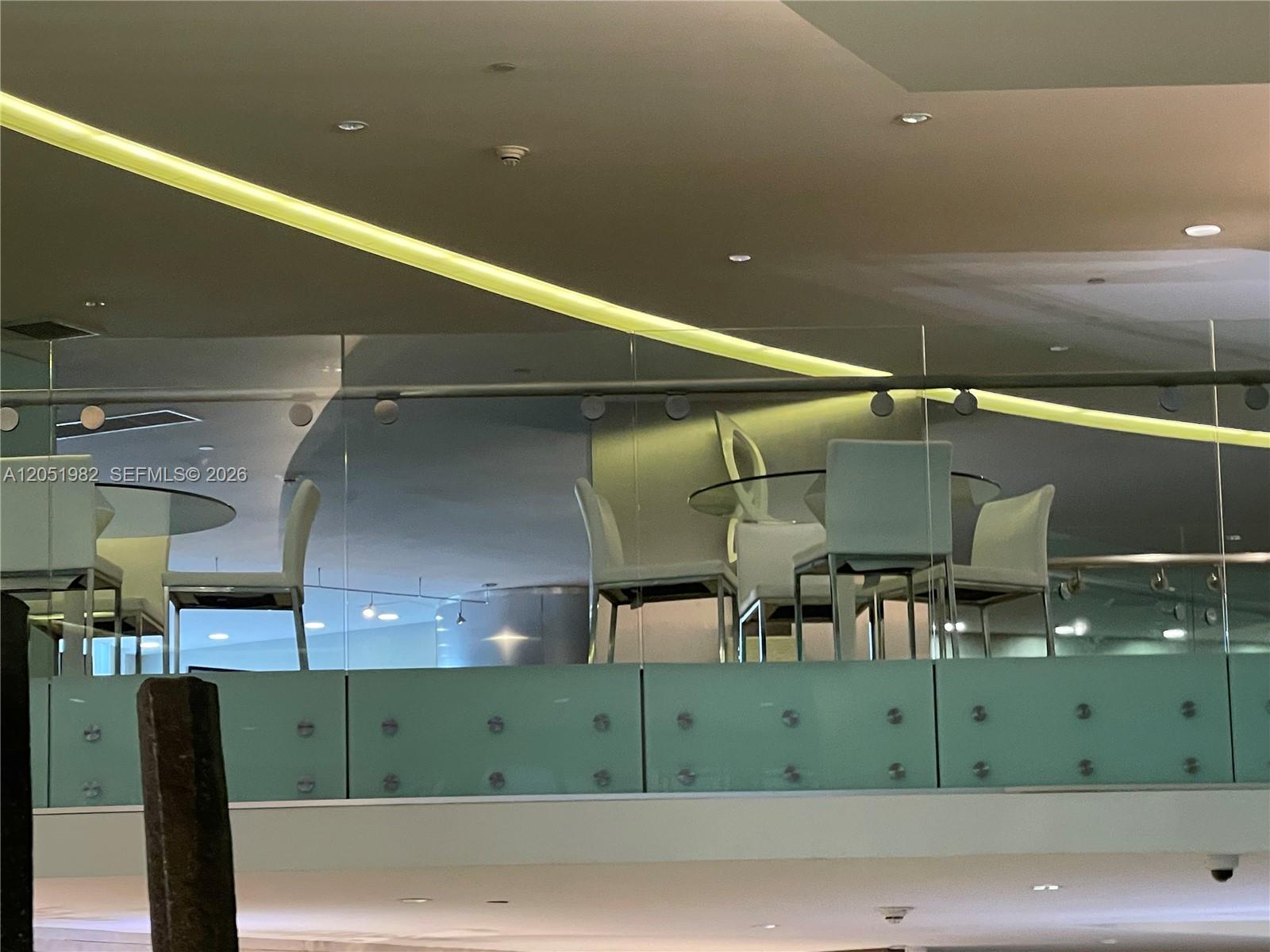 A dining area with white chairs and a glass table sits behind a glass railing — 92 SW 3rd St # 5012, Miami FL 33130, MIAMI, FL