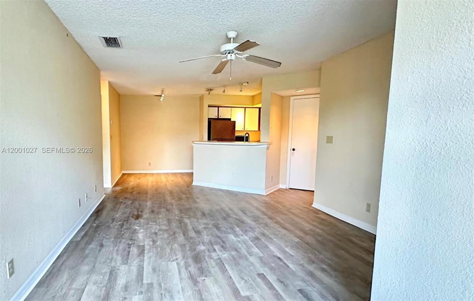 An interior view shows a living area with wood-look flooring, a ceiling fan, and a kitchen — 3310 N Pinewalk Dr N # 1823, Margate FL 33063, MARGATE, FL