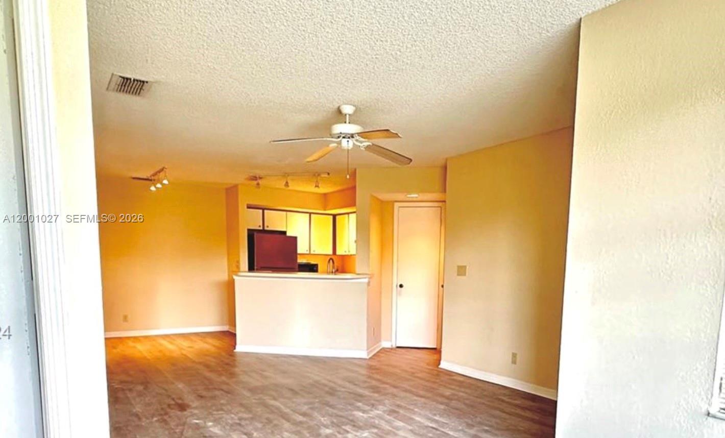 An interior view shows a living area with wood-look flooring and an open kitchen — 3310 N Pinewalk Dr N # 1823, Margate FL 33063, MARGATE, FL