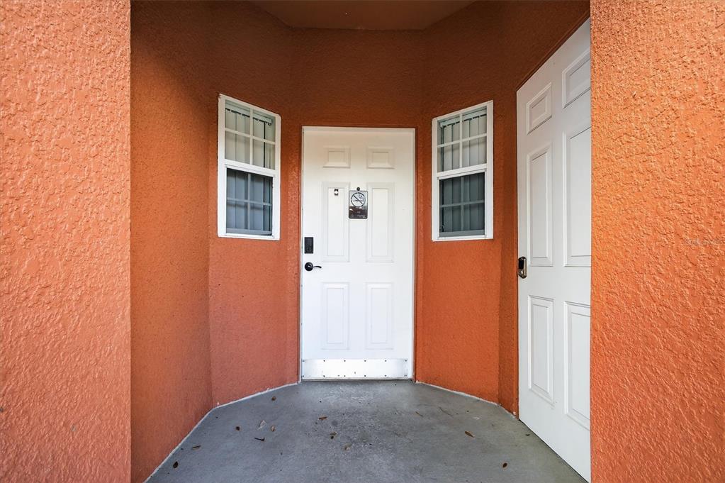 A recessed entryway features two white doors, two windows, and orange textured exterior walls — 1066 PARK RIDGE CIRCLE, KISSIMMEE, FL