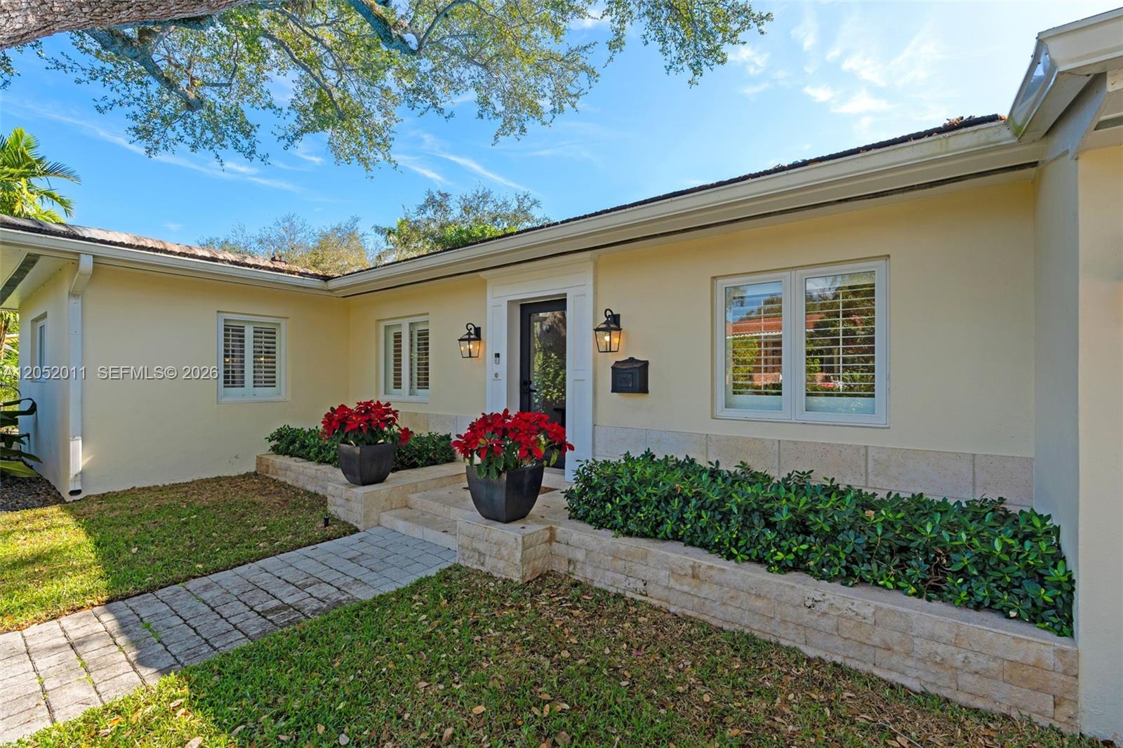 The exterior of a single-story home features a stone walkway, planters, and a front entrance — 168 Morningside Dr, Coral Gables FL 33133, CORAL GABLES, FL