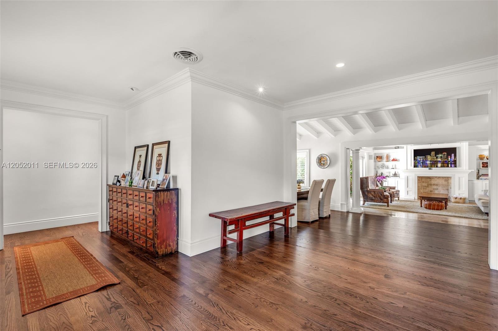 A spacious foyer with dark hardwood floors leads into a bright living room with columns — 168 Morningside Dr, Coral Gables FL 33133, CORAL GABLES, FL