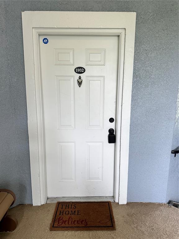 A white front door with a house number and a welcome mat on a porch — 3713 CONROY ROAD UNIT 1932, ORLANDO, FL