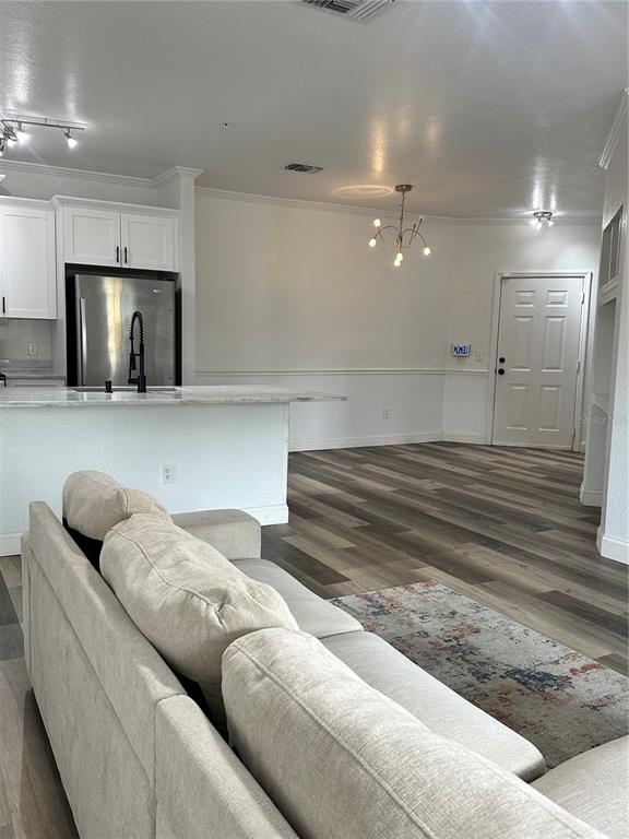 A living room with a sofa faces an open kitchen featuring white cabinets and counters — 3713 CONROY ROAD UNIT 1932, ORLANDO, FL