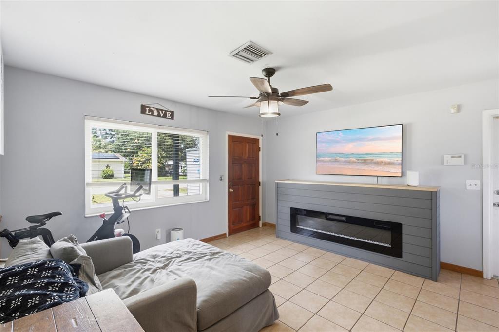 A living room features a gray shiplap fireplace, a wall-mounted television, and a stationary bike — 1597 SE TANGELO DRIVE, ARCADIA, FL