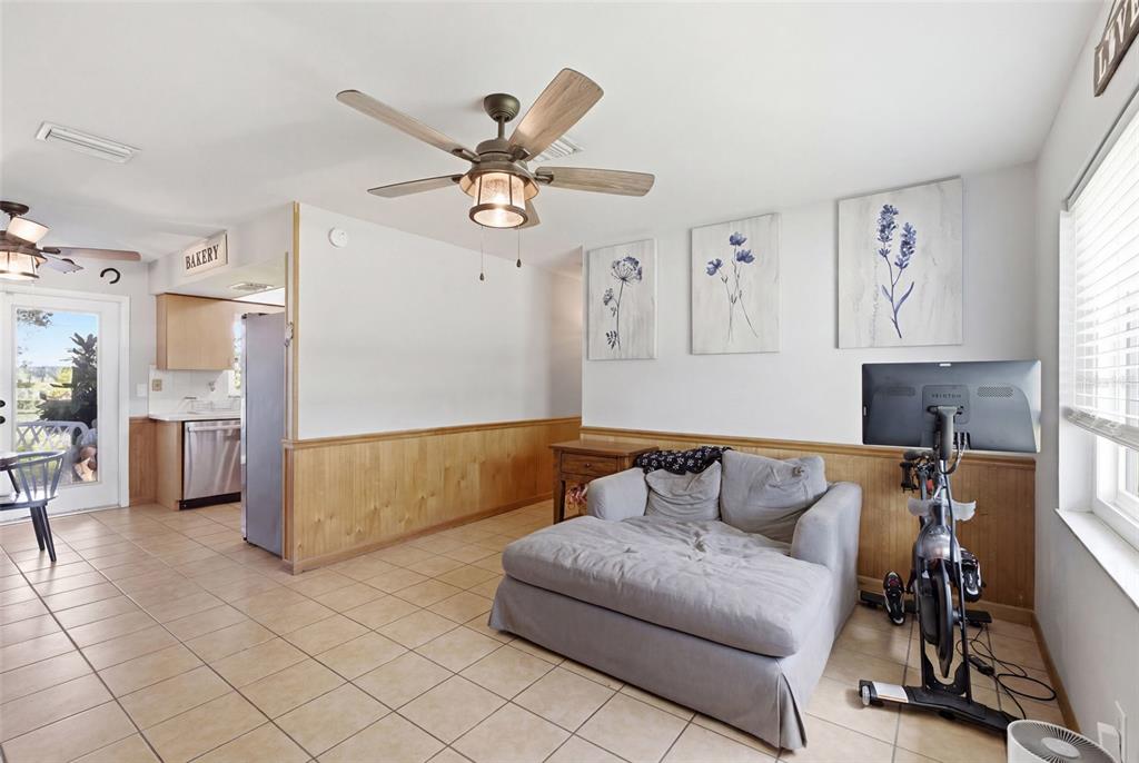A living area with tile floors, wood wainscoting, a gray chaise lounge, and a stationary bike — 1597 SE TANGELO DRIVE, ARCADIA, FL