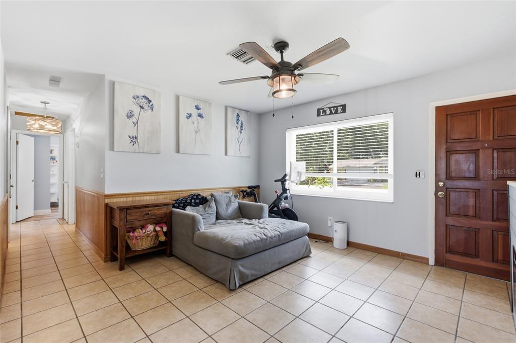 A room with tile flooring, a gray sofa, a stationary bike, and a wooden door — 1597 SE TANGELO DRIVE, ARCADIA, FL