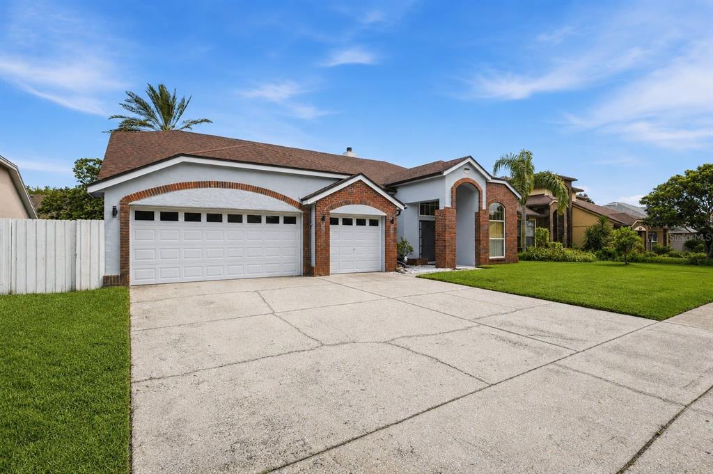 A single-story house with a brick-trimmed garage and arched entryway under a blue sky — 3716 GATLIN PLACE CIRCLE, ORLANDO, FL